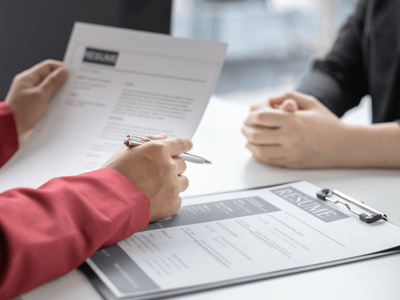 A recruiter reviewing a candidate's resume across a table during an interview